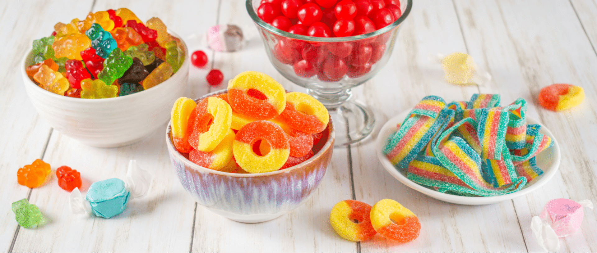 Colorful assorted candies in bowls on table.